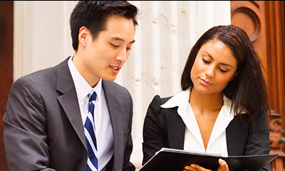 A man and a woman in business attire looking at a file