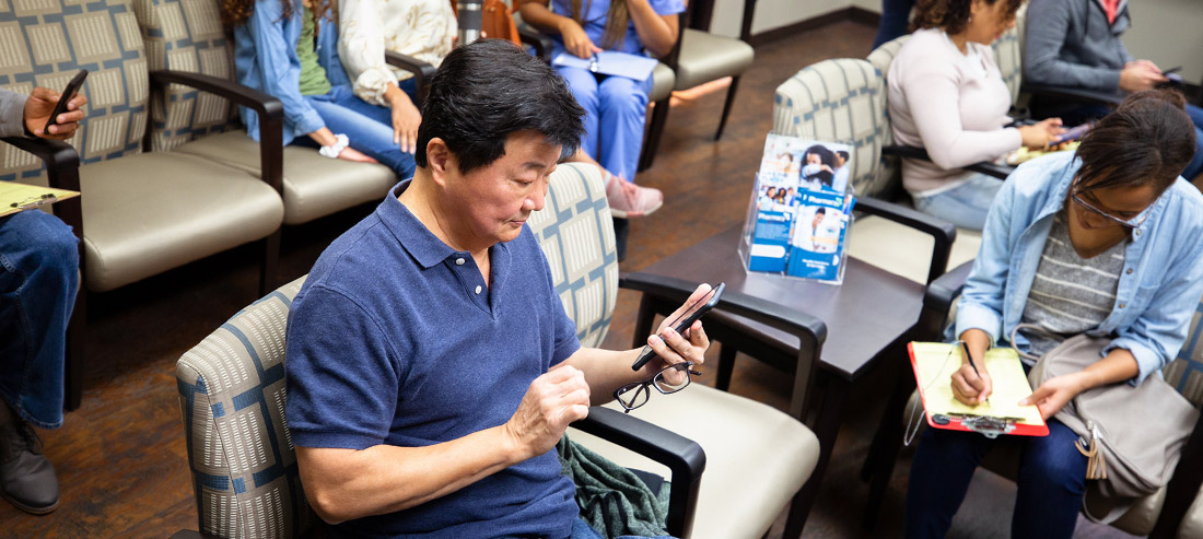 Asian man in a group setting on his cell phone