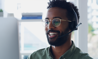 Man wearing glasses with headset on looking at computer screen