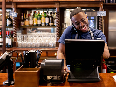 Male server on phone putting order into a POS computer 