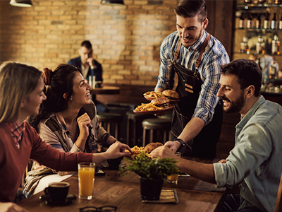 A server bringing food to a group of four at a table in a restaurant