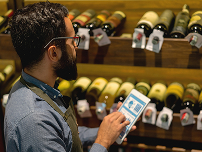 Male server taking inventory of wines on a tablet computer