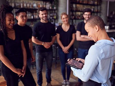 Restaurant manager standing in front of her servers with a tablet