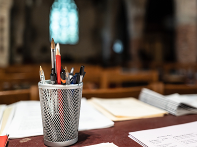 A desk with papers and a pencil cup holder inside of a church