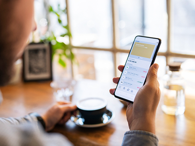 Man on phone accessing his bank account in a coffee shop