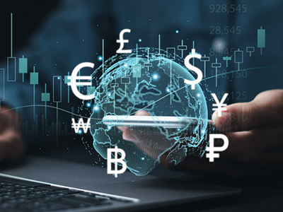 Graphic of a glob with various currency icons floating around it while a person is working on a laptop