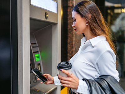 Person at the ATM of a bank while also on their phone