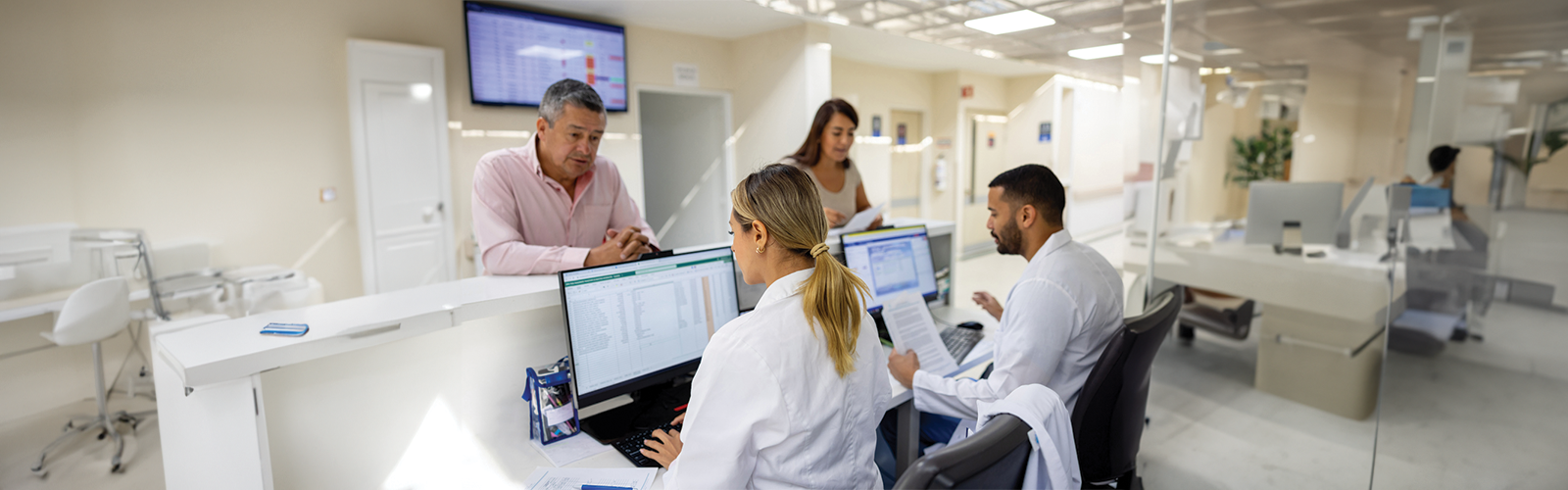 Two patients checking in at the front desk of a hospital