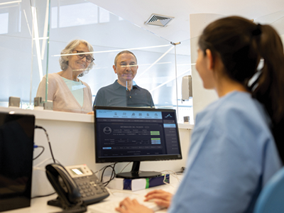 Female healthcare receptionist scheduling an older couple's appointment