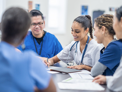 Group of medical professionals meeting around a table with documents and devices