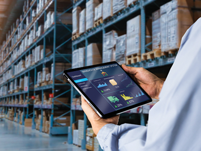 Customer in a warehouse holding a tablet that shows information about the warehouse inventory