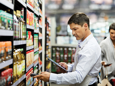 A worker in a grocery store using wireless technology to scan items on shelves