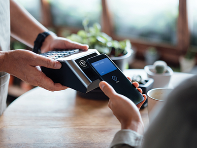 A pair of hands using a wireless point of sale system by paying with a credit card