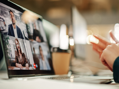 Headless person with hands visible sitting at a desk on their laptop in a virtual meeting