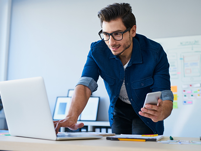 Man standing over a desk on his laptop