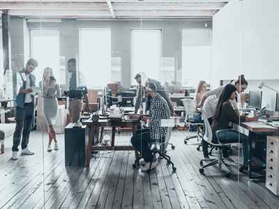 Young people in an open-concept office with computers on desks