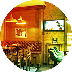 Empty bar with brick walls, padded booth, and tv turned on