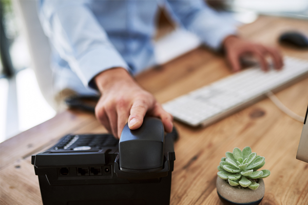 A male's hand holding the phone on a business telephone